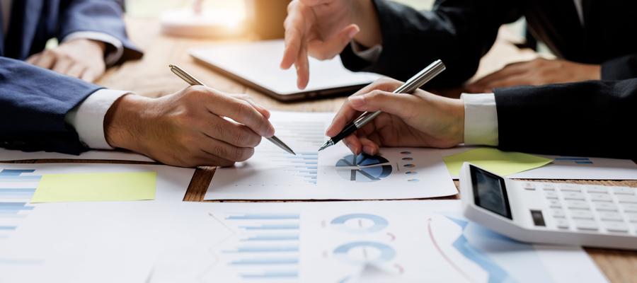 Finanzanalysten analysieren den Finanzbericht eines Unternehmens auf einem digitalen Tablet während der Diskussion in einer Sitzung